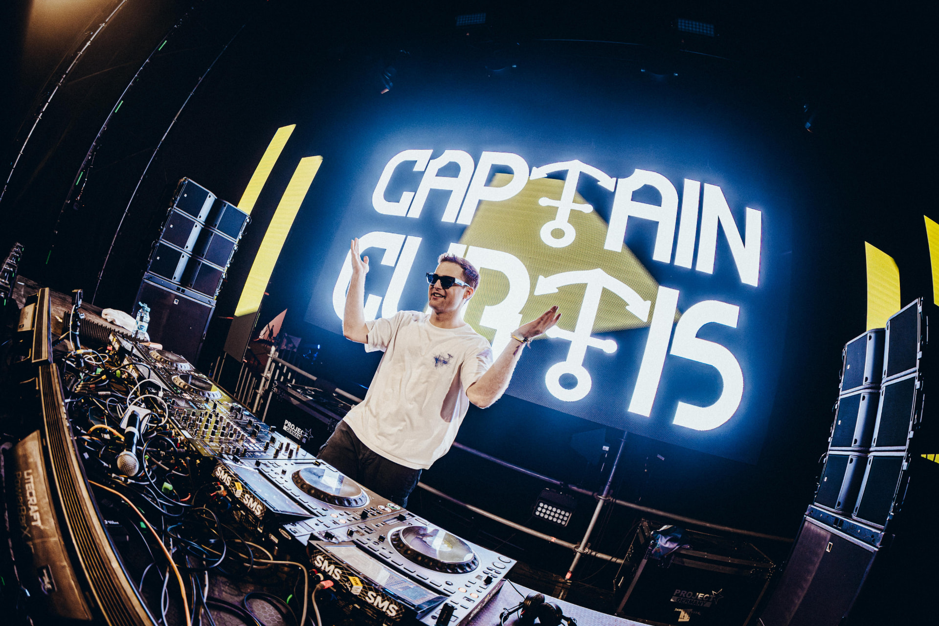 Captain Curtis on stage in front of a giant illuminated Captain Curtis screen
